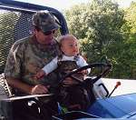 Great-grandson Cole riding the tractor with his grandfather and my son Corky who he calls 'Big Dada'